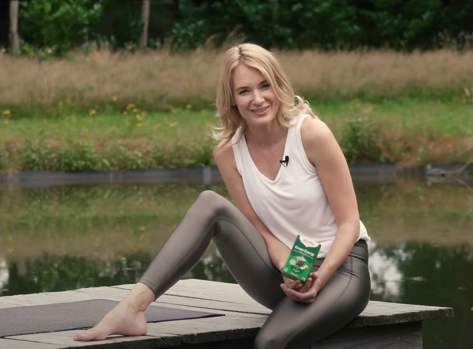 Mujer rubia sujetando una caja. Está sentada al lado de un lago