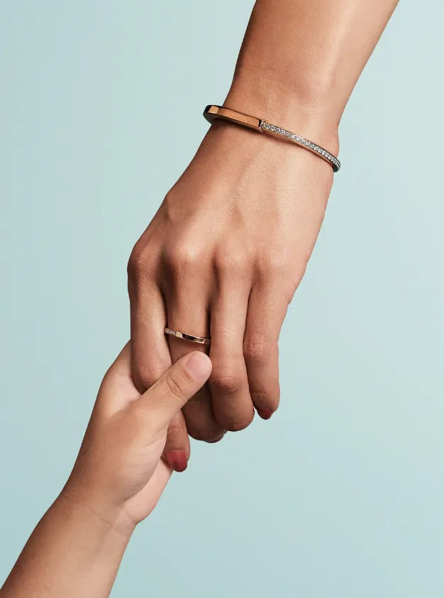 mujer con anillo y pulsera dorados sujetando la mano de un niño