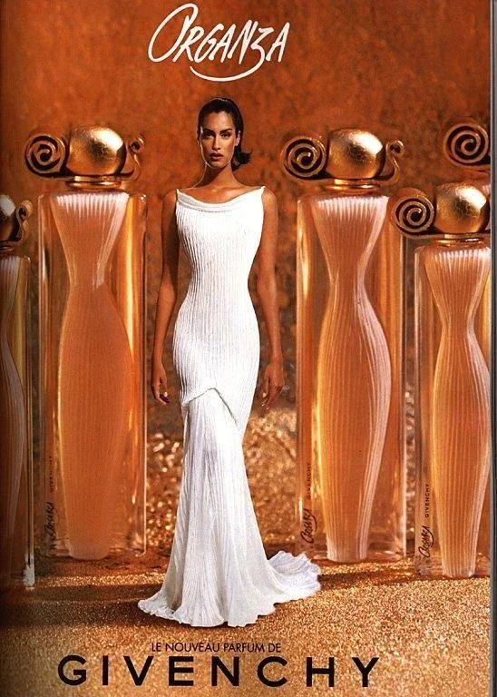 mujer con vestido blanco posa junto con varias esculturas