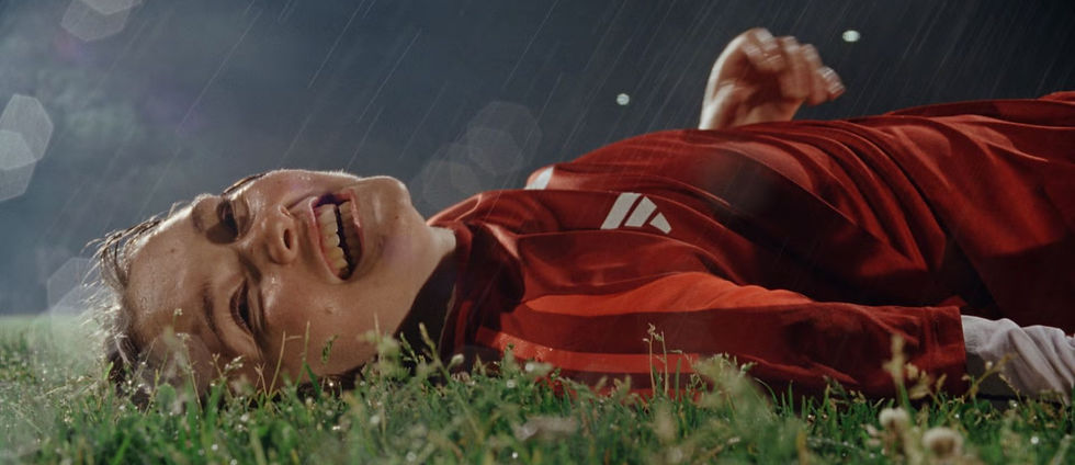 mujer futbolista tumbada en el césped riendo mientras llueve