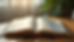 Eye-level view of an open Bible on a wooden table with soft natural light