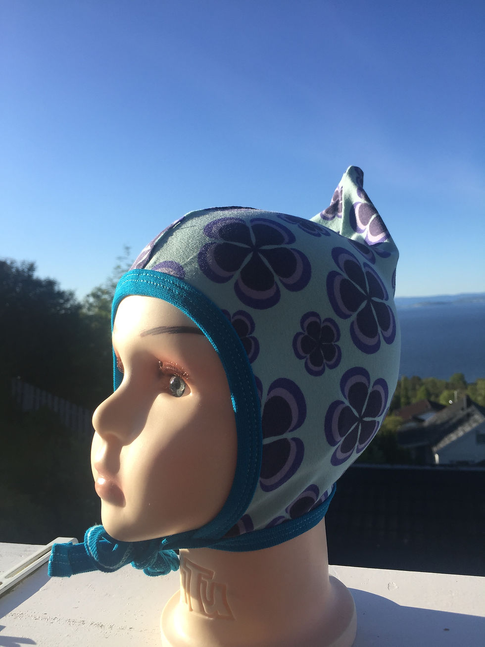 Knytelue med spiss sydd av blått stoff med retroinspirerte blomster. Håndlaget av Urk!