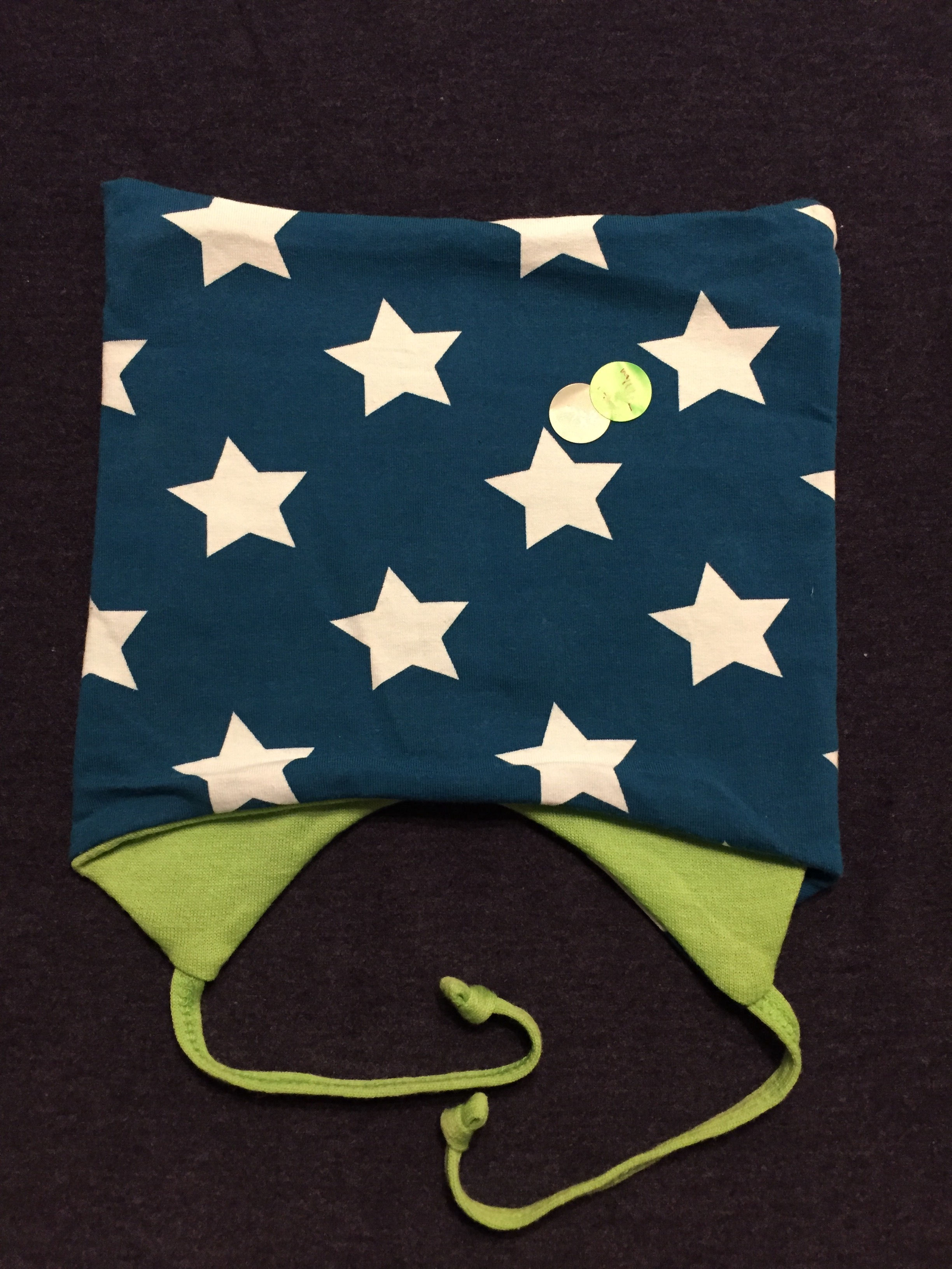 Blå firkantlue med stjerner. Lua har knyting under haka og er foret med ull. Håndlaget av Urk!