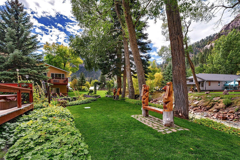 Riverside lawn with carved bear benches and gardens at River’s Edge Lodge in Ouray, Colorado