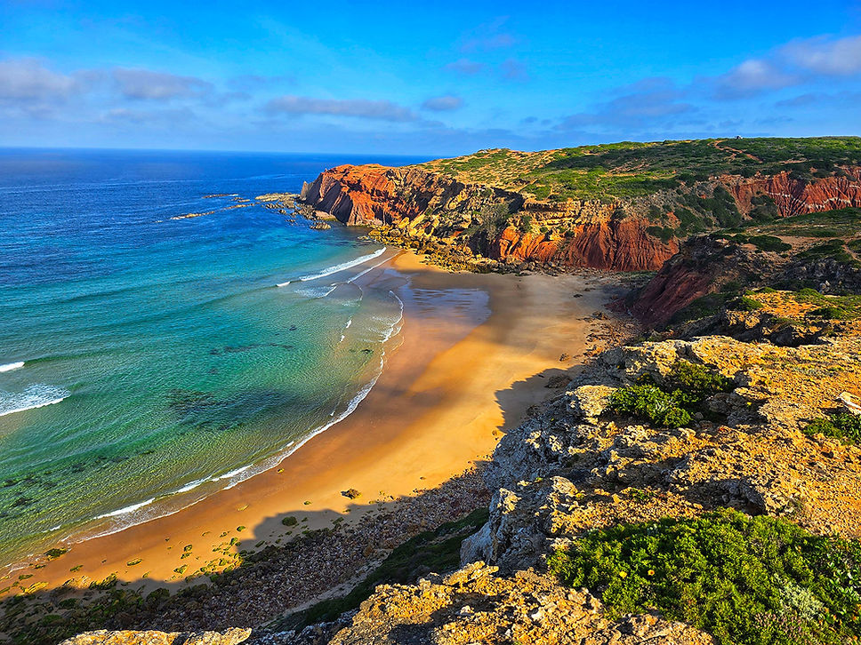 Scenic coastal view with beach, ocean, and red cliffs in Portugal