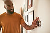 A man changing the temprature of his thermostat.