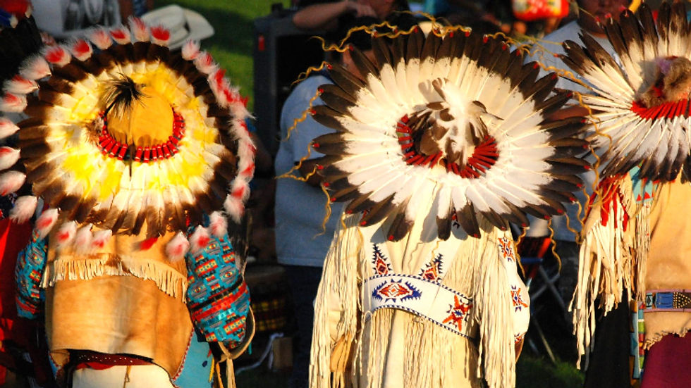 Native American people wearing eagle feather head dressings.