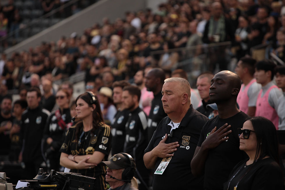 LAFC head of security and staff members stand with fans during the national anthem at BMO Stadium, moments before kickoff.
