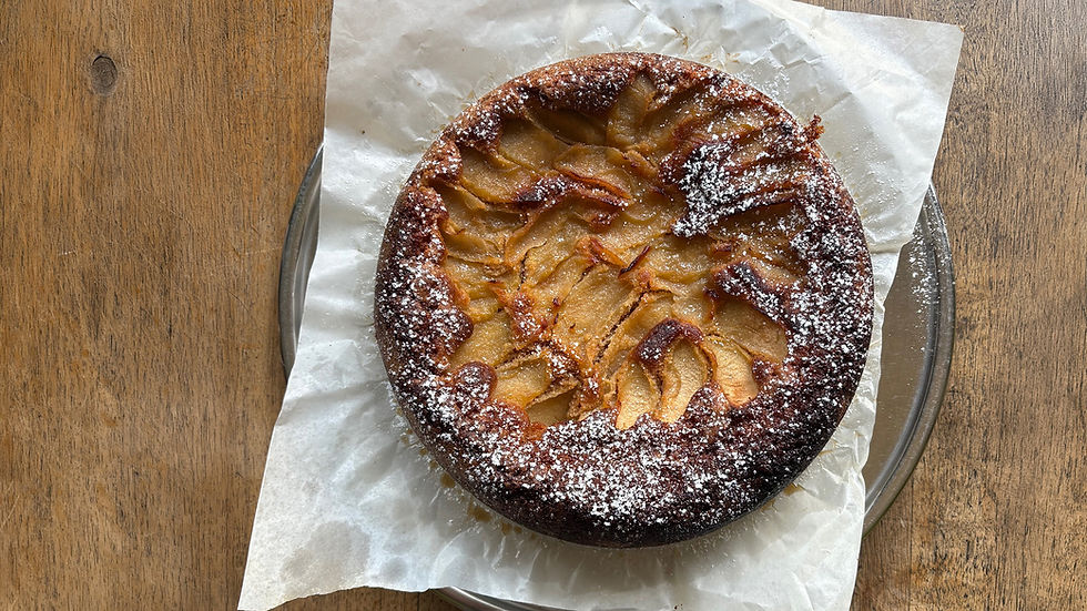 A photo of a round cake from the top view on timber table. The cake has icing sugar sprinkled on top.