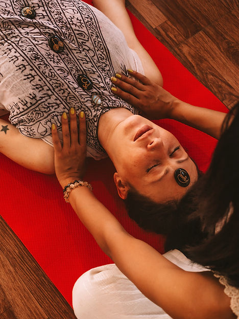 Close-up view of a person receiving a Reiki and crystal healing session, lying supine on a vibrant red mat with a crystal on their forehead.