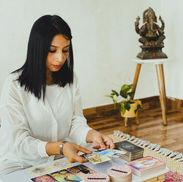 Professional tarot reader sitting at a table reviewing tarot and oracle card spreads during a session.