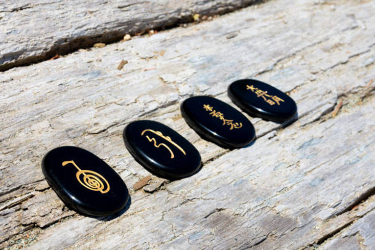 Traditional Usui Reiki symbols engraved on black stones for a certification course banner.