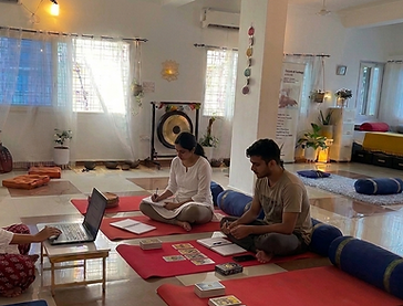Tarot teacher Sanghamitra conducting an intimate Tarot reading certification class in her serene studio, showing students how to interpret card spreads with their notebooks.