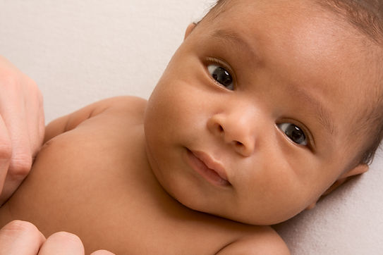 Thoughtful biracial mix of Hispanic and African American infant lying down on yellowish co