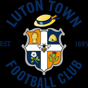 Luton Town Football Club crest with a straw hat above. Features symbols: wheat, beehive, flower, thistle. Text: "EST 1885." Blue and orange tones.
