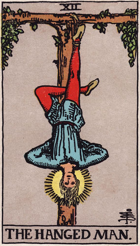 The Hanged Man tarot card from the Major Arcana, showing a man suspended upside down by one foot from a tree, with a halo around his head.