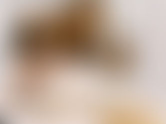 Casal jovem sentado à mesa da cozinha planejando o orçamento familiar pelo celular, em ambiente simples e acolhedor.