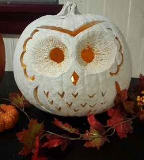 A cream-colored pumpkin painted with a black silhouette of a witch in profile, framed by an ornate oval border with a spider hanging from a web above her hat. The pumpkin is topped with a large orange bow with black polka dots, creating a stylish Halloween decoration.