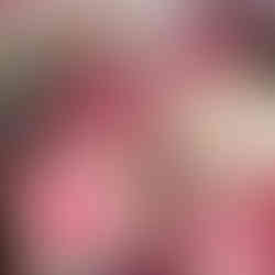 Children creating heart-shaped art using paint and stamps at a table covered with pink craft supplies.