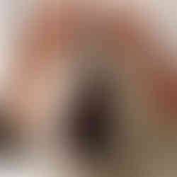 A white pumpkin decorated with a black silhouette of a witch wearing a pointed hat, framed by an ornate oval border. A small spider dangles from a web above her hat. The pumpkin is topped with a large orange ribbon featuring black polka dots, adding a festive Halloween touch.