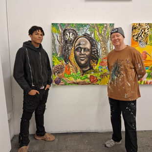 Kalik Allah and John Newsom standing in front a painting of Killah Priest for his album entitled Enter The Forest of The Happily Ever After.