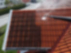 Uniformed member of staff pressure washing a tiled roof.