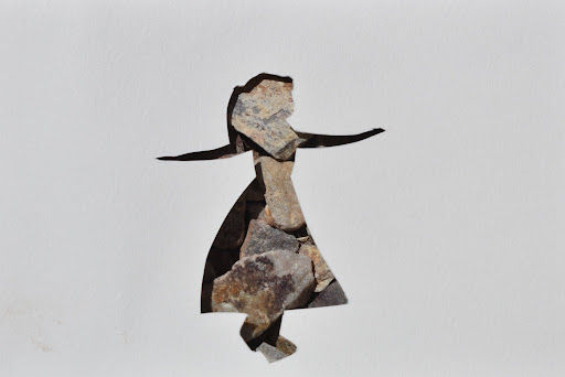 A girl in a dress cut out of paper with rocks in the background