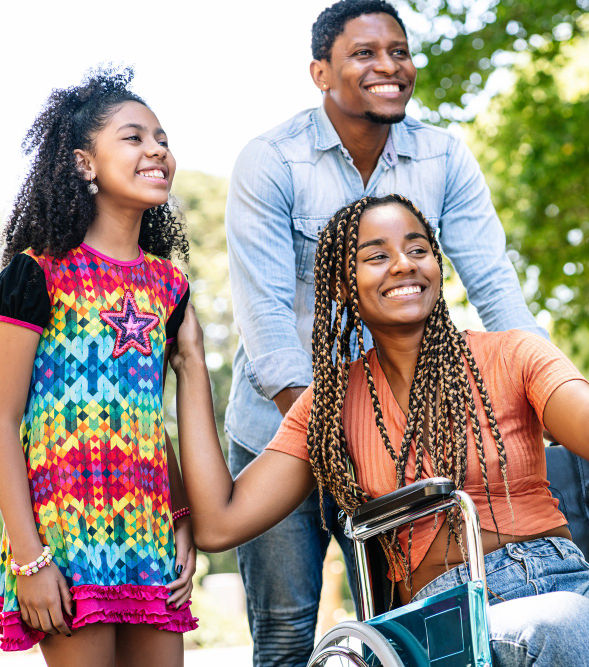 an-african-american-woman-in-wheelchair-enjoying-walk-outdoors-with-her-daughter-and-husba