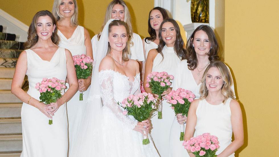 A bride and her maid of honour in elegant dresses sit closely, holding hands at a candlelit table in a white tent. A chandelier hangs above; guests in the background. Italian garden party inspired wedding complete with Limoncello, photographed by Danielle of Fineshade Studios.