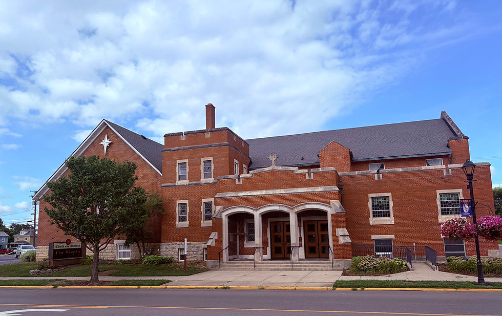 Landscape photo of a red-brick church exterior under a blue sky, wide landscape