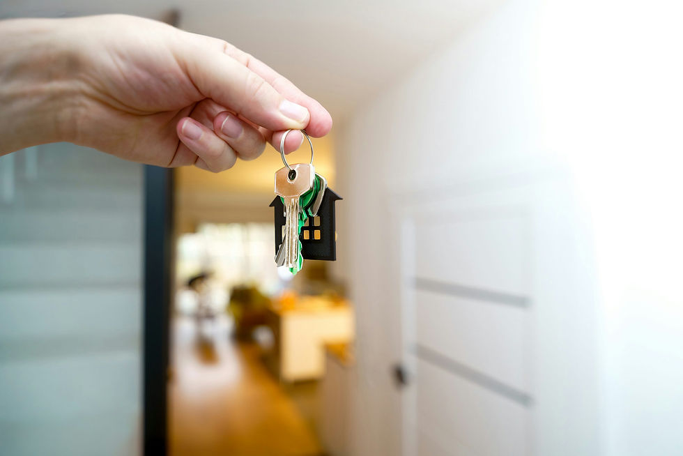 A hand holding house keys at the front door of a home