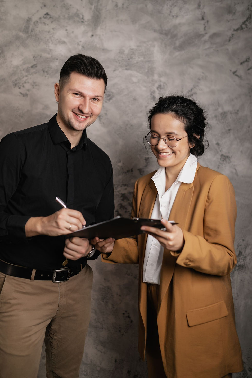 Two people signing real estate closing documents with a clipboard and pen