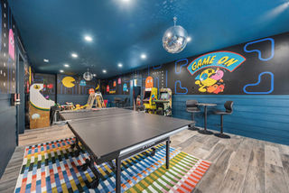 Custom game room mural for a vacation rental featuring retro Pac Man inspired artwork, colorful arcade graphics, and hand painted wall art that creates a memorable guest experience and encourages social media sharing.