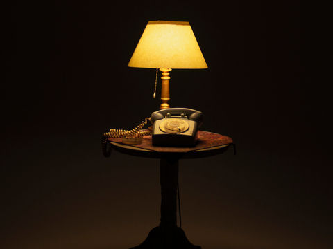 diorama miniatura de teléfono antiguo color cesleste sobre mesa con lámpara y cenicero con cigarros