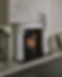Elegant marble fireplace with a black Chesneys Solstice gas fire, glass doors showing a fire. White and black candles on mantel. Vase of flowers nearby. Cozy setting.