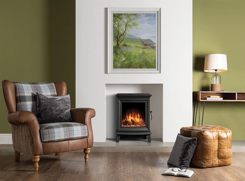 Cozy room with an armchair, plaid pillow, and ottoman. A Gazco Chesterfield 5 gas fire is lit under a landscape painting. Green walls, wooden floor, lamp, and open book.