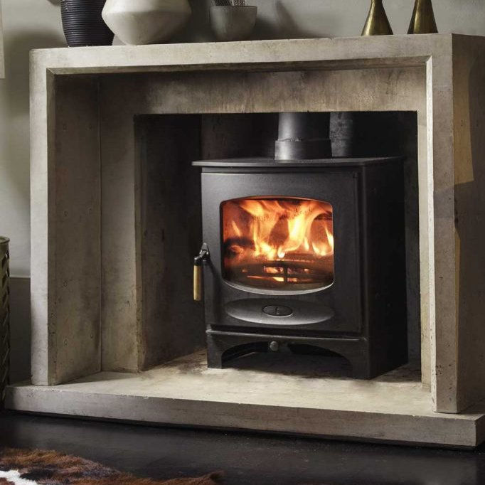 Lit Charnwood C Seven Woodburning Stove sat within a limestone surround