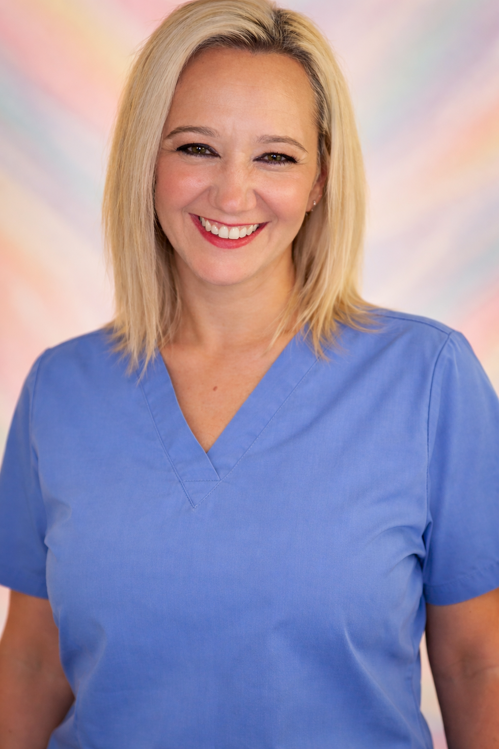 Smiling blonde woman in blue scrubs