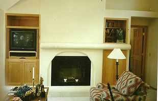 A simple interior plaster fireplace surround. Color is beige. Taken in the living room.