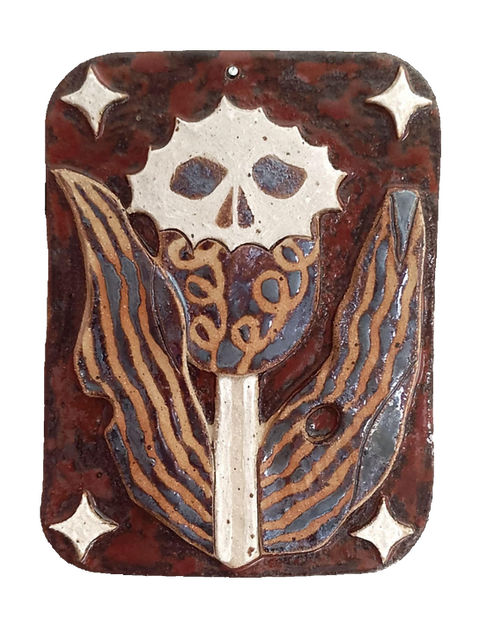 Ceramic wallhanging done i stoneware that depicts a thistle with skull