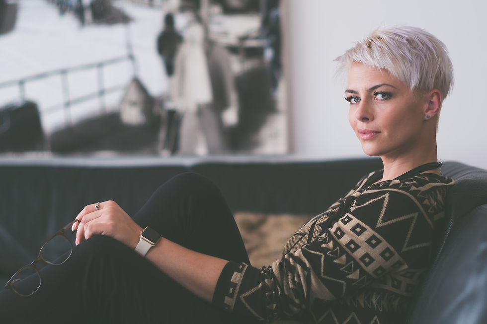 Woman with short white hair sitting looking sideways at the camera