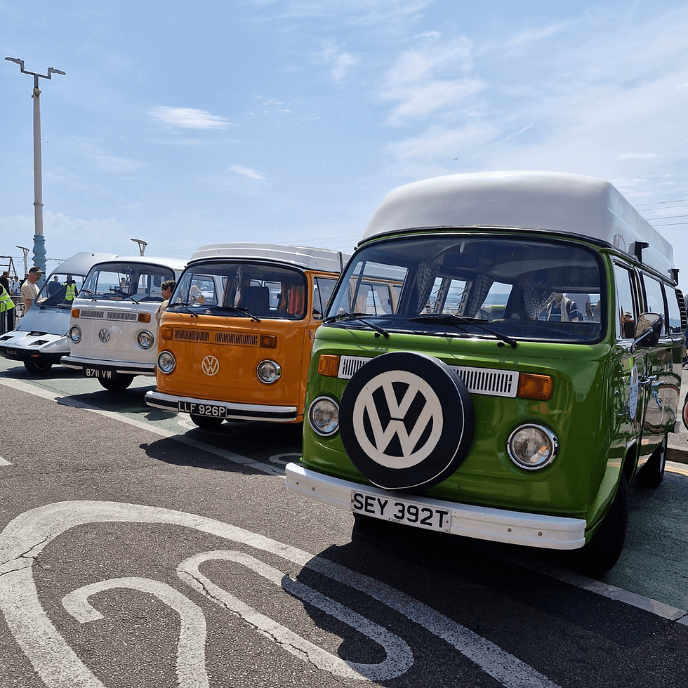 Image shows three VW Campers lined up on the seafront.