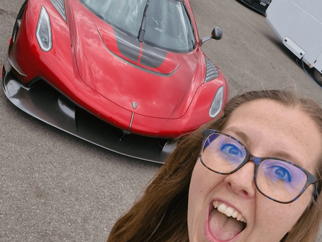 Belinda smiling in front of a red Koenigsegg