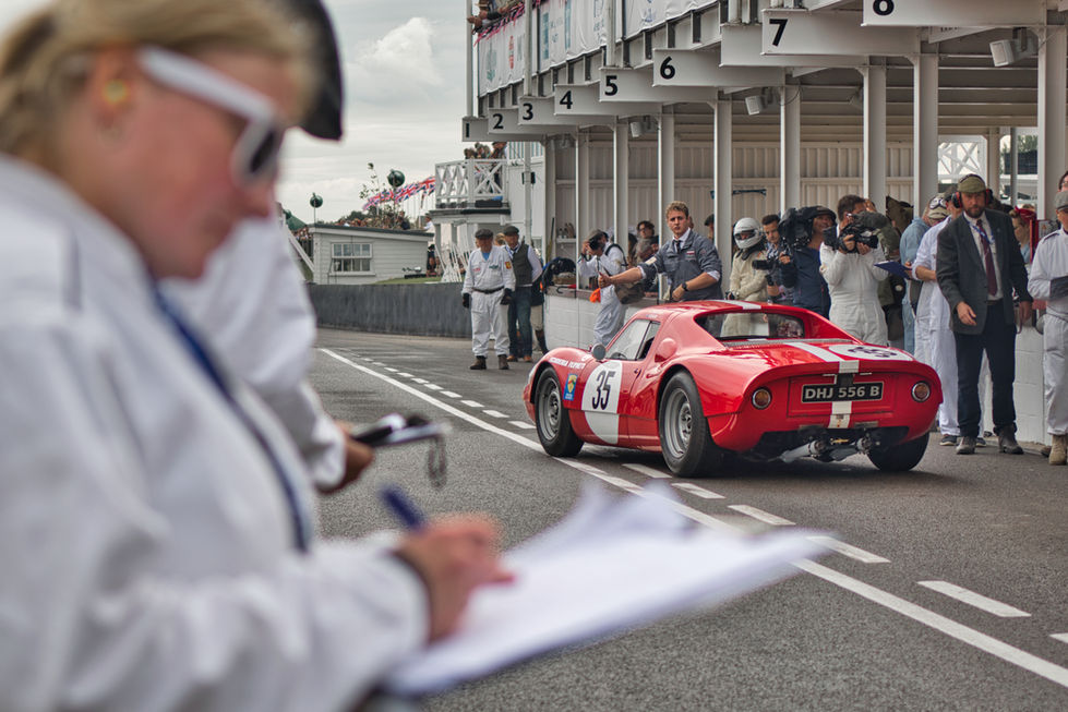 Red Porsche 904 in the pits at Goodwood Revival with marshall scrutineers in the foreground. 