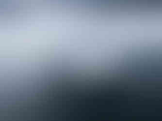 A large white ship on the water with four large windgsails.