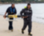 Two men are carrying an autonomous underwater vehicle (AUV) on the sea shore at a beach