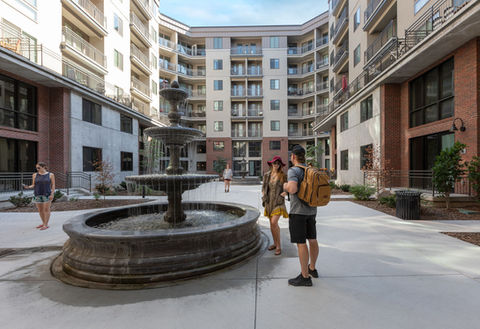 People talk in the common courtyard of Hardware Village. The building surrounds the courtyard