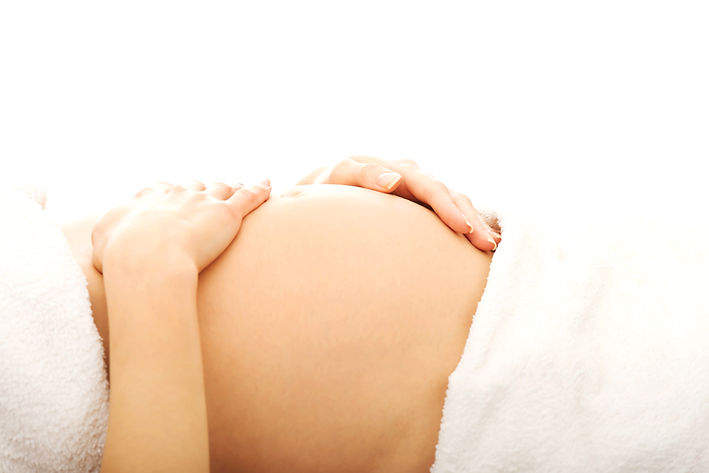 Pregnant woman massagin her growing belly.jpg