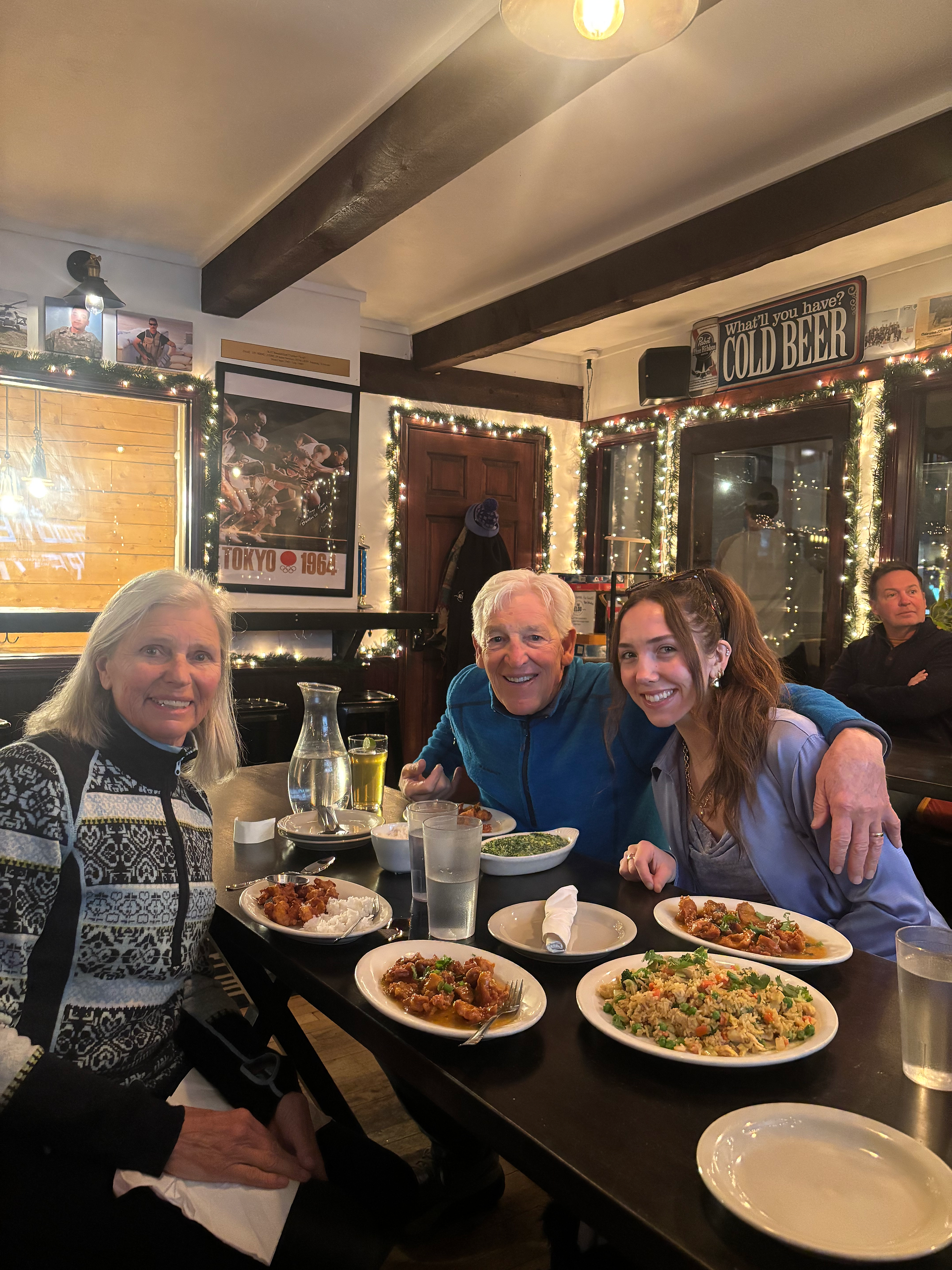 Three people at a table eating plates of nepalese food