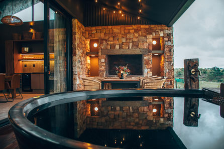 Patio with hot tub and illuminated stone fireplace